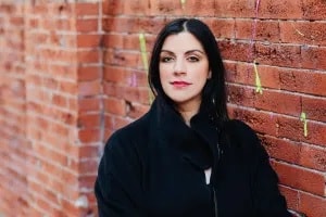 Image of author Erin Khar against older red brick wall.