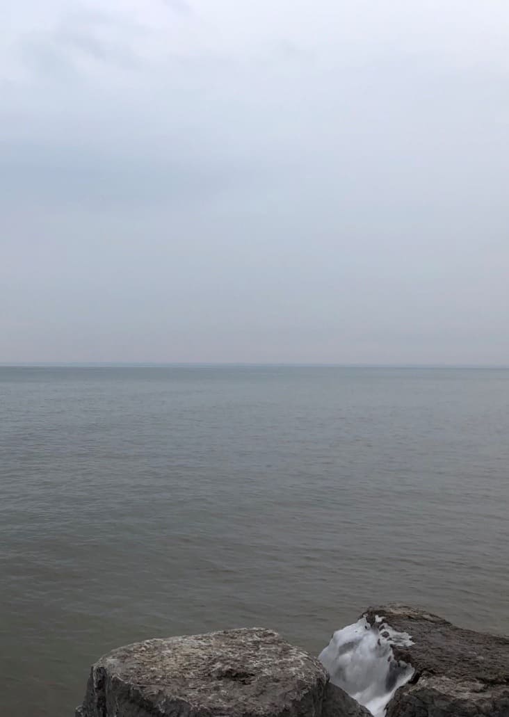 Grey toned water, sky, and stone, on a calm winter day, Lake Ontario looking S.