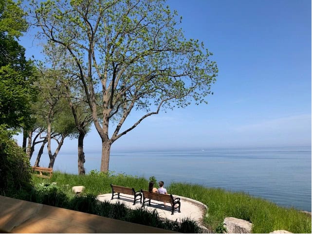 Author’s photograph of two people sitting at the north shore of Lake Ontario, Oakville, May 2024.