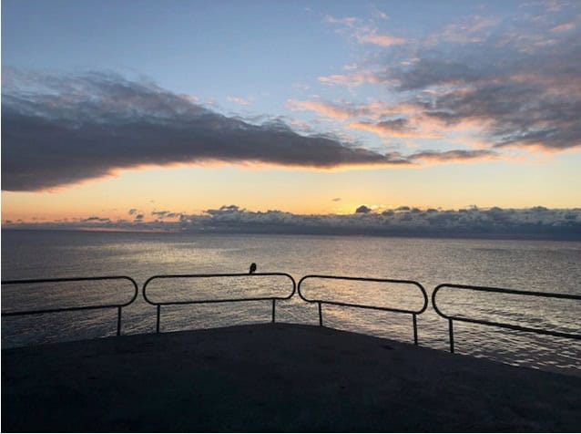 Dramatic blue and yellow clouds in a sunrising sky overlooking Lake Ontario from Oakville's East Pier.